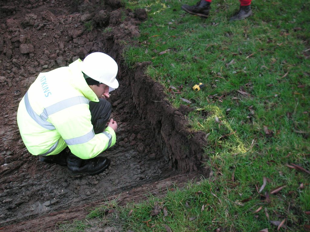 A geotechnical engineer examines the test pit wall